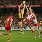 Australian Rules Football players competing during an AFL match in a packed stadium