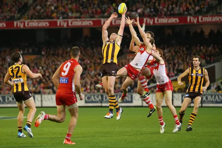 Australian Rules Football players competing during an AFL match in a packed stadium