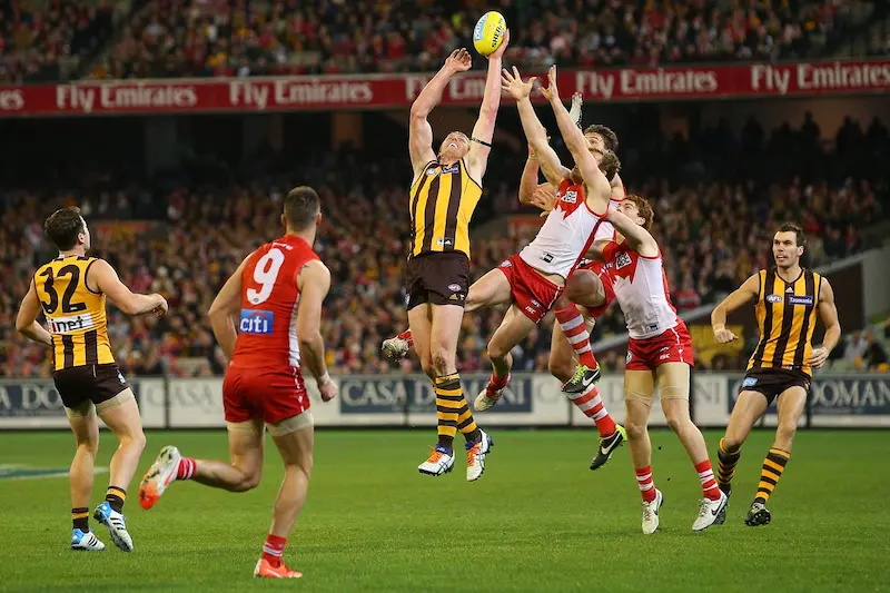 Australian Rules Football players competing during an AFL match in a packed stadium